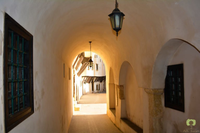 A vaulted passage running beneath a house, lit by a single lantern.
