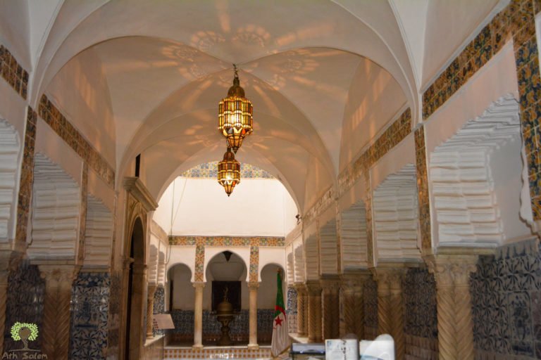 A vaulted vestibule with a hanging lantern and an arched doorway beyond.