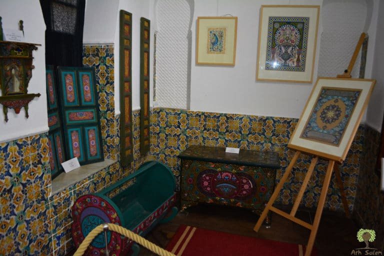 A tiled room in use as a gallery, work set out on easels.