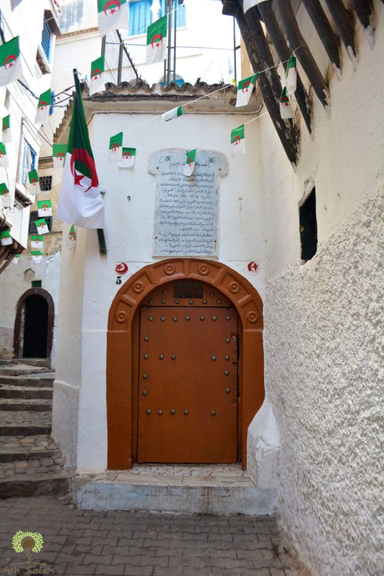 A studded timber door at the top of a whitewashed stair, the flag above it.