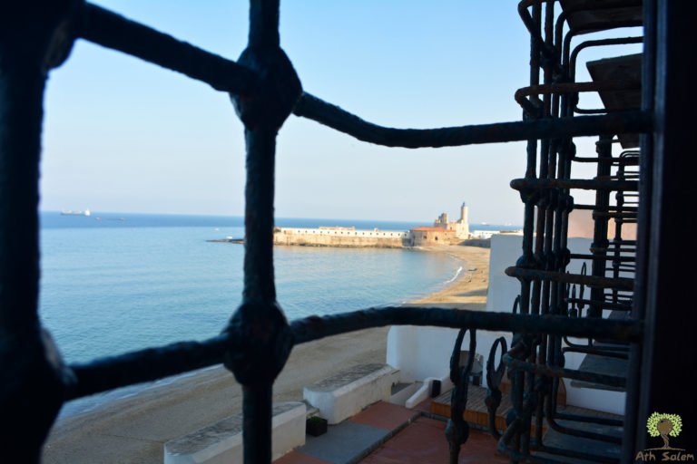 The harbour seen through a wrought iron window grille.