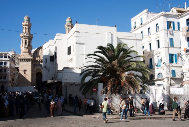 A square in the lower Casbah, a minaret rising behind the rooftops.